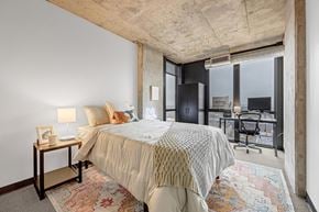 Denver apartment for rent - A bedroom with a large bed and a desk with a chair.