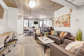 Denver apartment for rent - A modern office space with a couch, chairs, and a television.