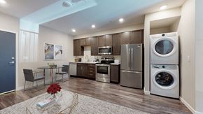 Denver apartment for rent - a kitchen with stainless steel appliances and a washer and dryer and a table