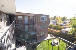 Englewood apartment for rent - A balcony overlooks a brick building and a green lawn.