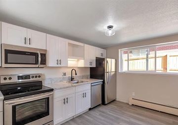 Denver apartment for rent - A kitchen with white cabinets and a black stove top oven.