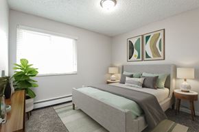 Arvada apartment for rent - A bedroom with a bed, two lamps, and a potted plant.