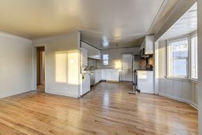 Denver apartment for rent - A spacious kitchen with wooden floors and white walls.