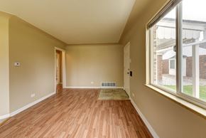 Denver apartment for rent - A room with wooden floors and a window overlooking a brick building.