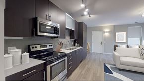Denver apartment for rent - A modern kitchen with dark brown cabinets and stainless steel appliances.at The Logan Apartments, Denver, CO 80203