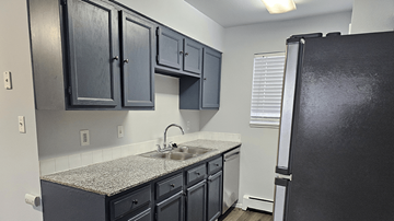 Greeley apartment for rent - A kitchen with black cabinets and a granite countertop.