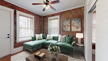 Denver apartment for rent - a brick walled living room with a green couch and a ceiling fan