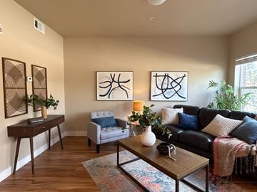 Fort Collins apartment for rent - A living room with a couch, chair, and two abstract paintings on the wall.