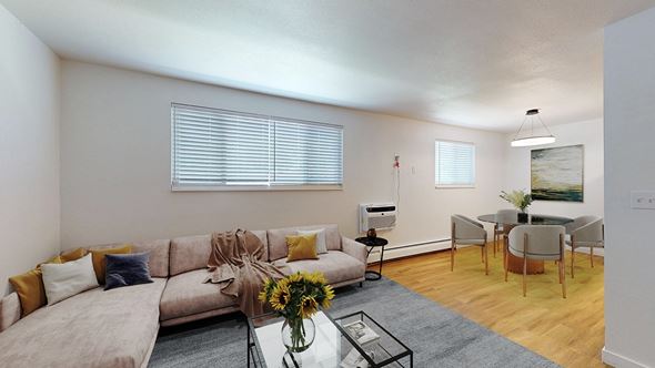 Arvada apartment for rent - A living room with a grey couch, a glass coffee table, and a dining table with chairs.