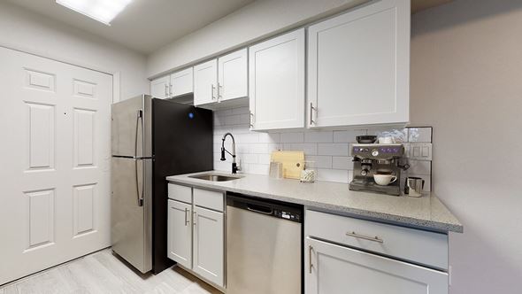 Arvada apartment for rent - A kitchen with white cabinets and a black refrigerator.