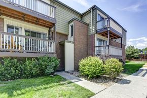 Arvada apartment for rent - A building with a balcony and a small garden in front.