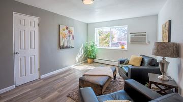 Littleton apartment for rent - A living room with a white door, a brown couch, and a painting on the wall.