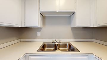 Denver apartment for rent - A kitchen with a double sink and white cabinets.
