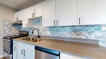 Denver apartment for rent - A kitchen with white cabinets and a blue tile backsplash.