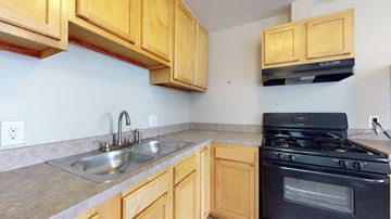 Denver apartment for rent - A kitchen with wooden cabinets and a black stove top oven.