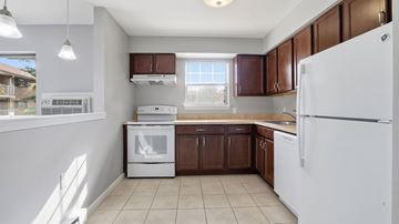 Bethlehem apartment for rent - A white refrigerator is in the corner of a kitchen with brown cabinets.