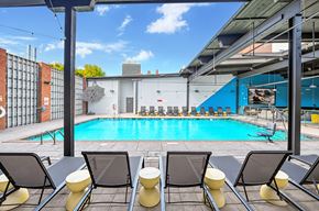 Winston-Salem apartment for rent - A pool surrounded by chairs and a building in the background.