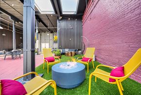 Winston-Salem apartment for rent - A brightly colored outdoor seating area with yellow chairs and a blue table.