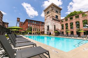 Atlanta apartment for rent - a swimming pool with chaise lounge chairs and umbrellas in front of a brick building