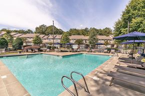 Athens apartment for rent - a swimming pool with chairs and umbrellas at the enclave at woodbury apartments