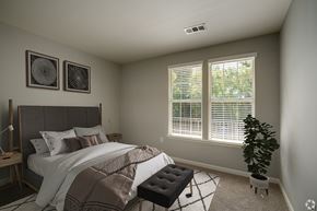 Glen Mills apartment for rent - A bedroom with a bed, a bench, and two wall art pieces.