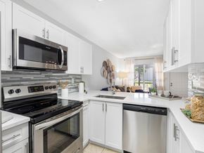 Boca Raton apartment for rent - A modern kitchen with white cabinets and stainless steel appliances.
