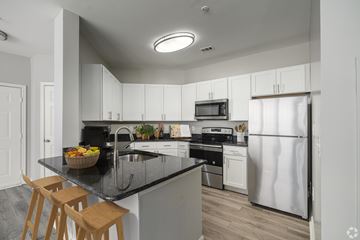 Glen Mills apartment for rent - A kitchen with white cabinets and a black countertop.