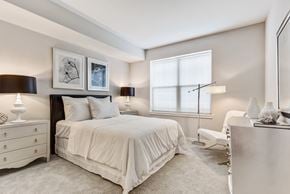 Vernon Hills apartment for rent - Apartments for Rent in Vernon Hills, IL - The Oaks of Vernon Hills - Cozy Bedroom With Plush White Bedding, Framed Wall Art, Soft Carpet, Dual Nightstands, and Wide Window With Blinds.