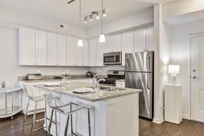 Vernon Hills apartment for rent - 1-Bedroom Apartments in Vernon Hills, IL - The Oaks of Vernon Hills - Bright White Kitchen With Granite Island, Bar Seating, Pendant Lights, and Stainless Steel Appliances