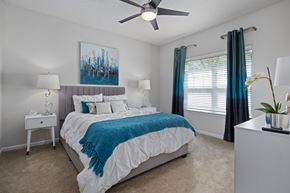 Raleigh apartment for rent - A bedroom with a bed, a ceiling fan, and a painting on the wall.