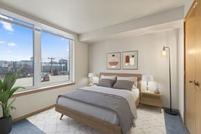 Seattle apartment for rent - A bedroom with a large bed and a view of the city outside the window.