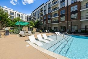 Charlotte apartment for rent - A swimming pool surrounded by lounge chairs and apartment buildings.