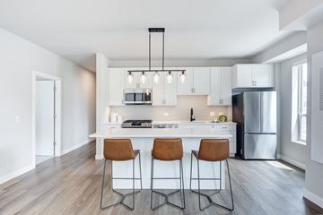 Downers Grove apartment for rent - A kitchen with white cabinets and a white island with three barstools.