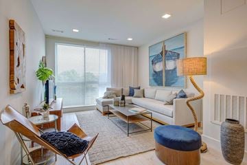 Revere apartment for rent - A living room with a white couch, a blue ottoman, and a large painting on the wall.