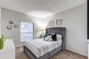 Austin apartment for rent - A bedroom with a large bed and a window with blinds.