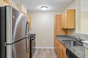 Littleton apartment for rent - A kitchen with a stainless steel refrigerator and wooden cabinets.