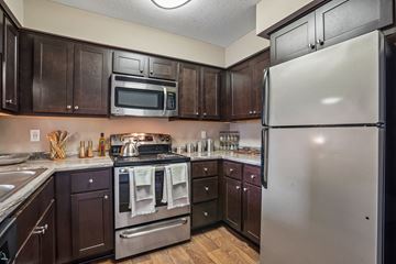Eden Prairie apartment for rent - A kitchen with dark wood cabinets and stainless steel appliances.