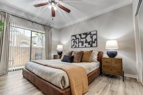 Houston apartment for rent - A bedroom with a bed, a ceiling fan, and a painting on the wall.