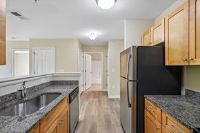 Littleton apartment for rent - A kitchen with a black fridge and wooden cabinets.