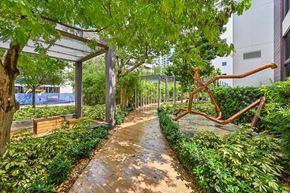 West Palm Beach apartment for rent - A walkway in a park with a bench and a sculpture.