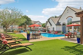 Round Rock apartment for rent - A pool area with a table and chairs and a building in the background.