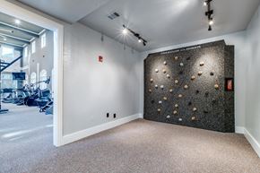 Houston apartment for rent - A room with a climbing wall and a gym in the background.