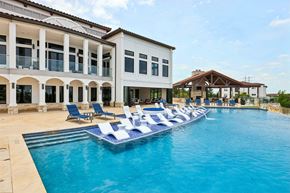 Austin apartment for rent - A large swimming pool with lounge chairs in front of a white building.