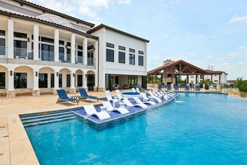 Austin apartment for rent - A large swimming pool with lounge chairs in front of a white building.