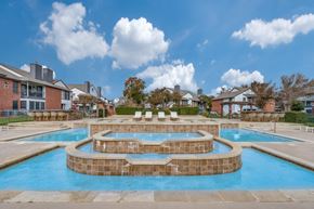 Austin apartment for rent - A large outdoor swimming pool with a hot tub in the middle.