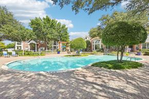 Plano apartment for rent - A swimming pool surrounded by trees and a brick patio.