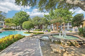 Plano apartment for rent - A beautiful outdoor scene with a fountain, trees, and a swimming pool.