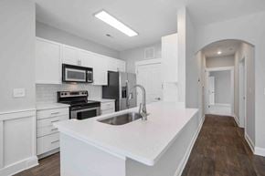 Charlotte apartment for rent - Charlotte, NC, Apartments Near Harris Teeter - The Apartments at Blakeney - Kitchen with Breakfast Bar, White Maple Cabinetry, Quartz Countertops, and Stainless Steel Appliances.