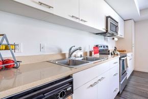 Seattle apartment for rent - One Bedroom Apartments in Green Lake Seattle WA - Circa Green Lake - Kitchen with White Cabinets, Beige Countertops, and Stainless Steel Appliances.