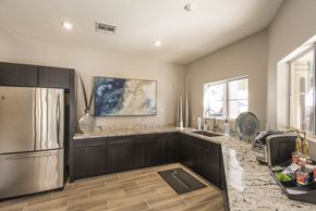 Phoenix apartment for rent - Apartments in Ahwatukee, AZ - Pacific Bay Club - Kitchen with Tiled Floor, Stainless Steel Appliances, Granite Countertops, Dark Wood Cabinetry, Windows, and Framed Artwork.
